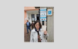 Elettrice con sindrome di Down davanti al seggio elettorale con in mano la sua scheda per votare